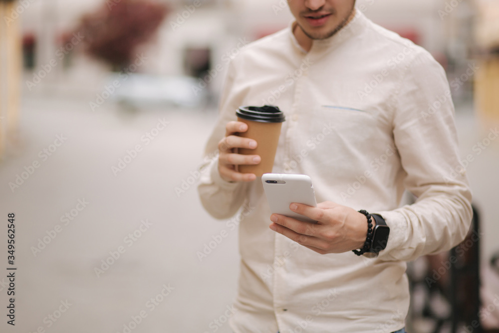 Fototapeta premium Middle selection of man stand in the city with cup of coffee and use phone