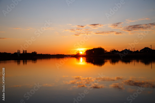 Sunset on the lake, the sun sets behind the trees and beautiful reflections in the water