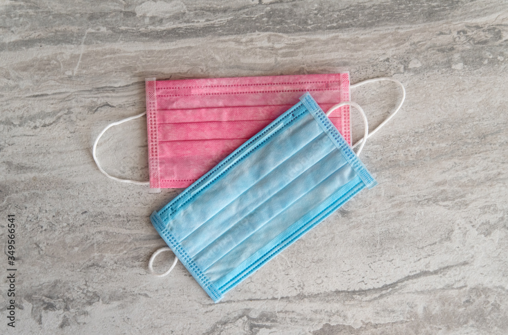 Two medical masks pink and blue lie on a gray textured background. Coronavirus protection concept Two medical masks pink and blue lie on a gray textured background. Coronavirus protection concept