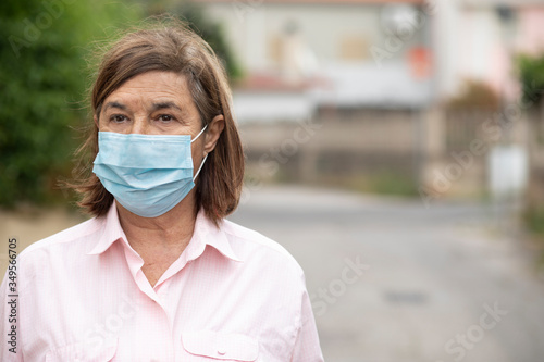 Ritratto di signora anziana che indossa una mascherina chirurgica isolata su sfondo strada