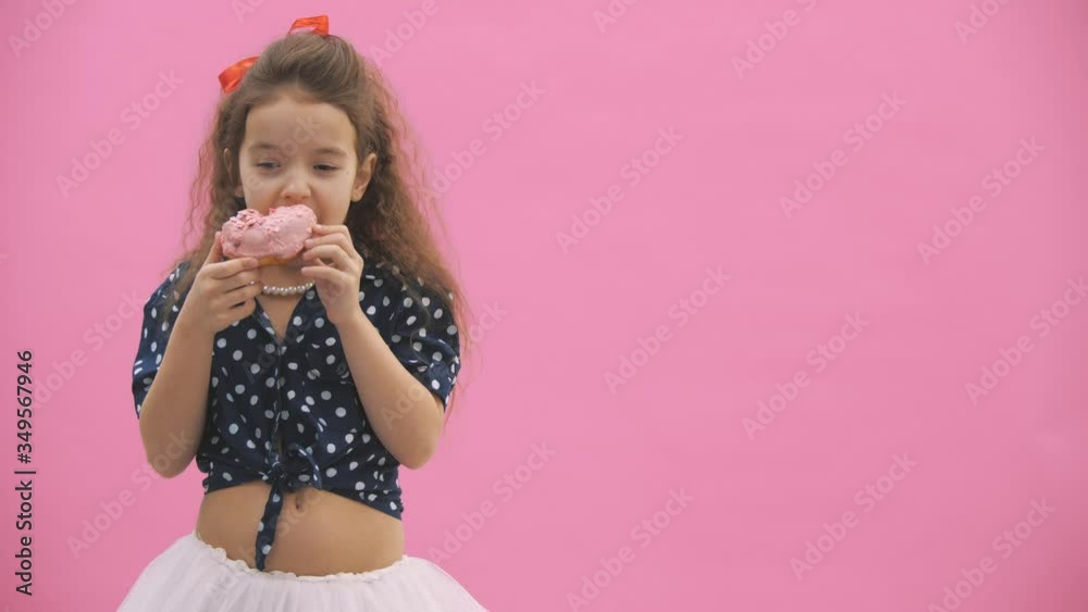 Little girl dressed in polka dot eats delicious donuts in 4k video. Little girl dressed in polka dot eats delicious donuts in 4k video.