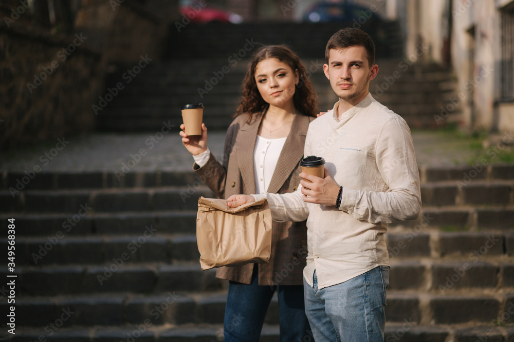 Young couple hold takeaway food in hands and smile to camera. Space for text