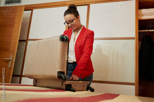 A beautiful female unpacking her suitcase in a hotel room