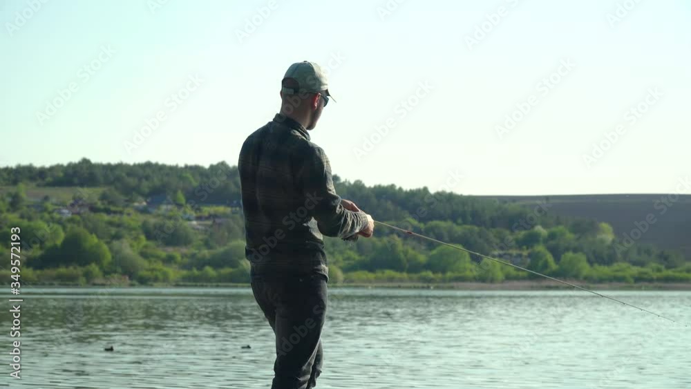 Fisherman cast fishing rod in lake or river water. Spinning fishing predatory fish Fisherman cast fishing rod in lake or river water. Spinning fishing predatory fish