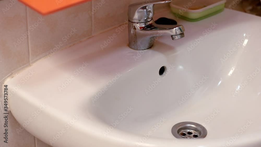 Person with latex gloves sprays basin with bleach and wash with scrubber in bathroom. House cleaning, disinfection concepts Person with latex gloves sprays basin with bleach and wash with scrubber in bathroom. House cleaning, disinfection concepts