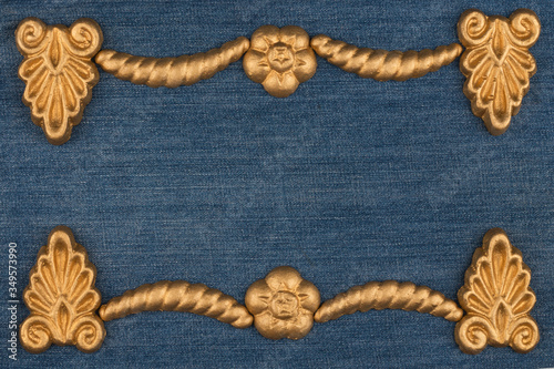 Frame made of gold-painted plaster molding lying on denim. Copy space. Top view.