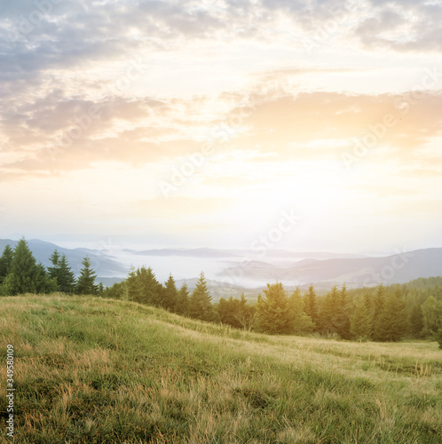 mountain valley at the early morning, rising sun above misty mountain