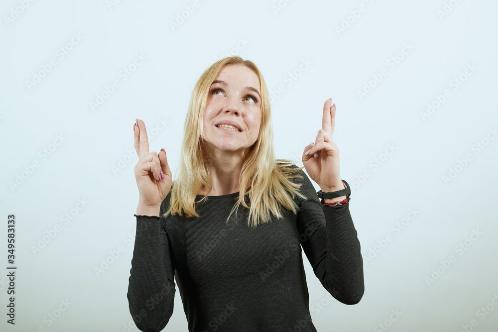 Young Blonde Woman In Black Sweater With Stylish Watch On White Background, Girl Feels That She Was Lucky. Lady Held Up Hands And Crossed Her Fingers. The Concept Of People Waiting. Young Blonde Woman In Black Sweater With Stylish Watch On White Background, Girl Feels That She Was Lucky. Lady Held Up Hands And Crossed Her Fingers. The Concept Of People Waiting.