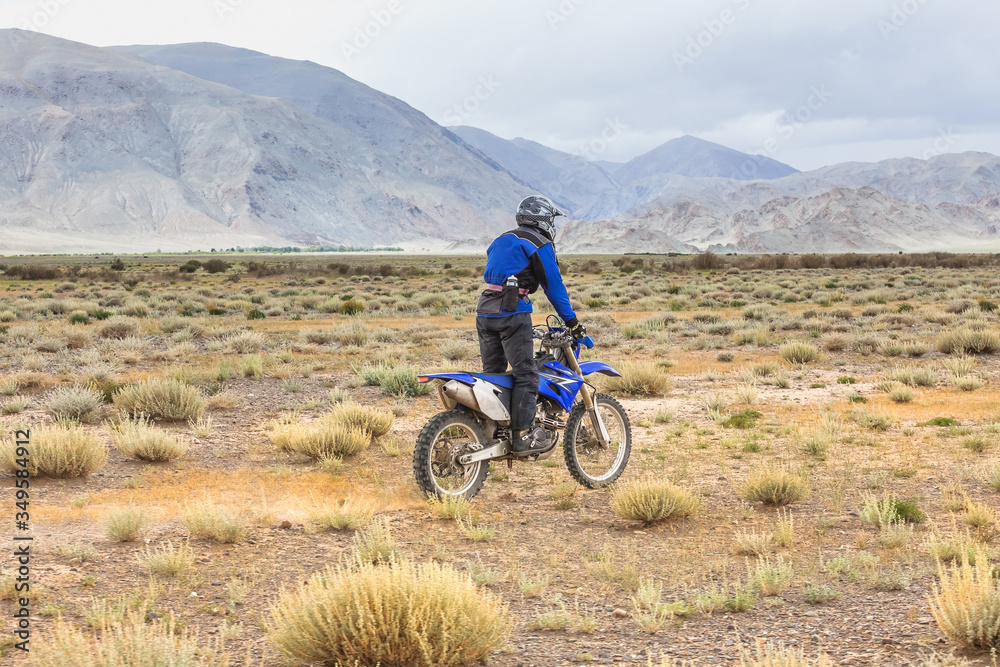 Man riding a motorbike in the steppes of Mongolia, on the hills of Mongolia