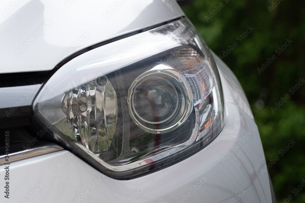 The front light of the car. Modern halogen lighting. Front lighting of a silver car