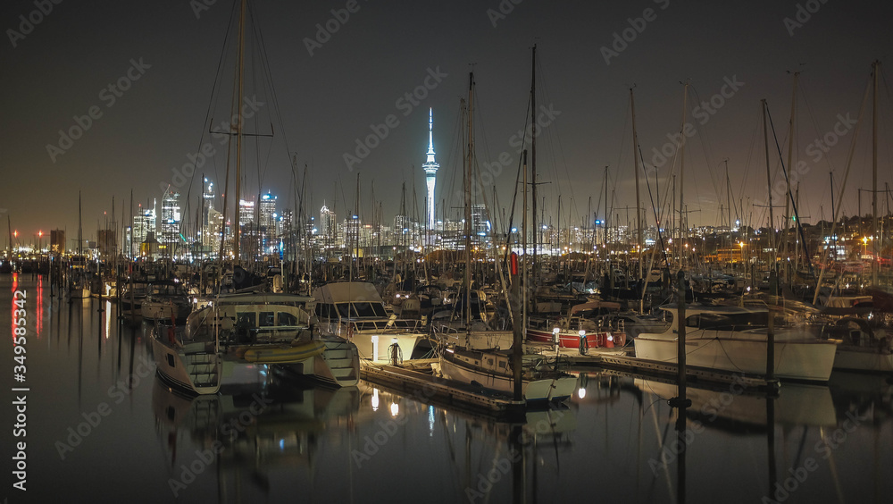 Night skyline view of Auckland with light-up sky tower and yachts reflection on the Auckland bay water,  Westhaven Marina, City of Sailing, New Zealand