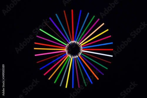 colored pencils are stacked in a circle with the point towards the center in the shape of a sun on a black background