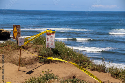 San Diego  CA USA May 14  2020  Warning signs for social distancing and bright yellow police warning tape closing the paths along the cliffs and beach at Sunset Cliffs in San Diego