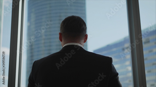 Photography Young successful businessman standing in front of the windows, looking into the distance to the city