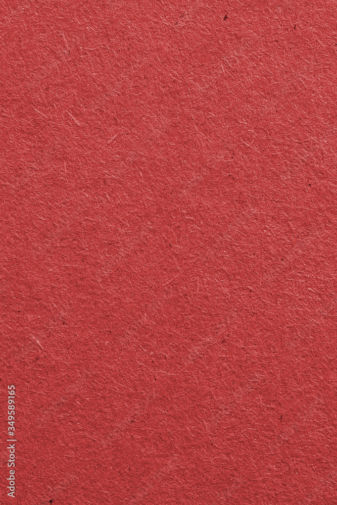 Fototapeta premium The surface of dark red cardboard. Rough paper texture with cellulose fibers. Saturated color. Vertical background or wallpaper. Top view from above. Macro