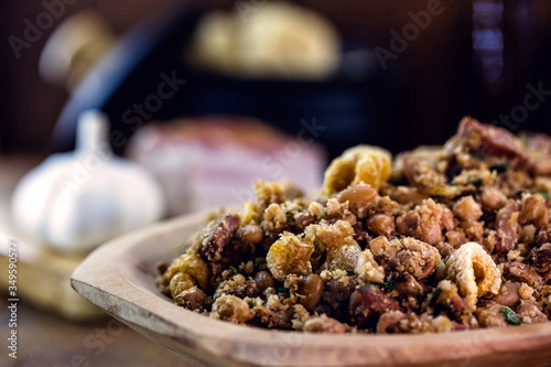 Beans with pork, called tropeiro beans in Brazil, typical Brazilian food, with ingredients, vegetables and vegetables in the background. Brazilian cuisine. photo