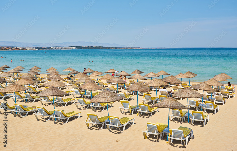 Fototapeta premium Empty sunbeds and parasols on morning, by the sea. Sand beach in luxury hotel resort near sea. Beautiful morning seascape.