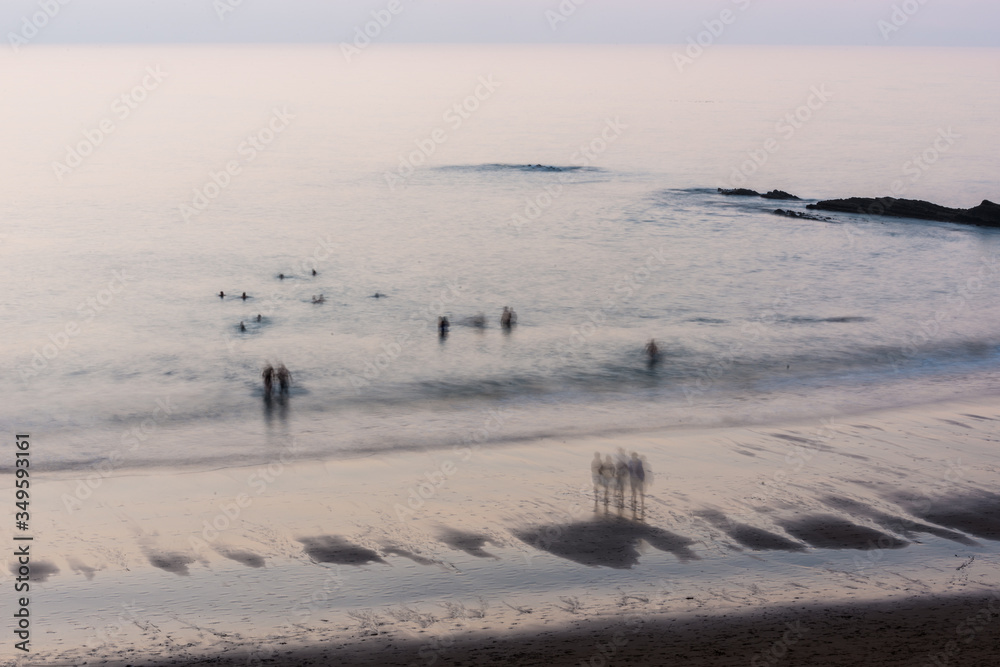 Obraz premium People taking their last swim at sunset on Zumaia beach