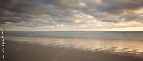 long exposure image of sandy beach and clouds