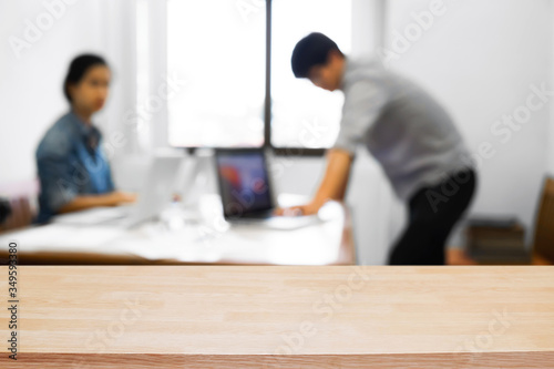 Empty wooden desk space over blurred office or meeting room background. Product display montage.