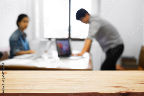 Empty wooden desk space over blurred office or meeting room background. Product display montage.