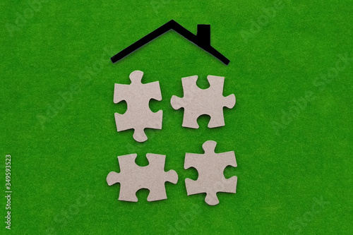 The roof is black, with four pieces of cardboard puzzles on a green background. House components.