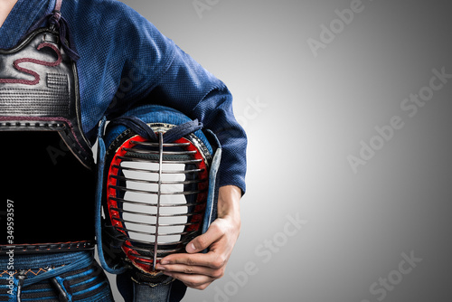 male in in tradition kendo armor with helmet in hand. shot in studio. isolated on grey background