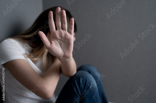 Concept of stop to gender violence. Woman sitting on the floor has her arm stretched out and the palm of her hand open making the stop gesture.