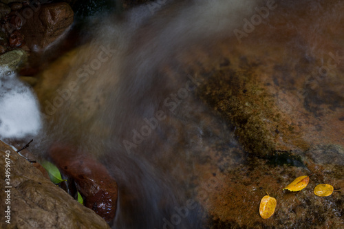 Long exposure close up landscape with waterfall and leaves, flowing water