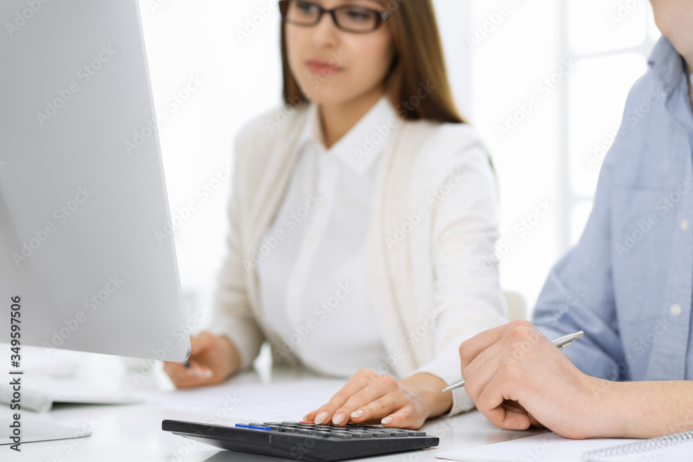 Bookkeeper checking balance with calculator or making finance report, close-up of hands. Tax and audit concepts Bookkeeper checking balance with calculator or making finance report, close-up of hands. Tax and audit concepts