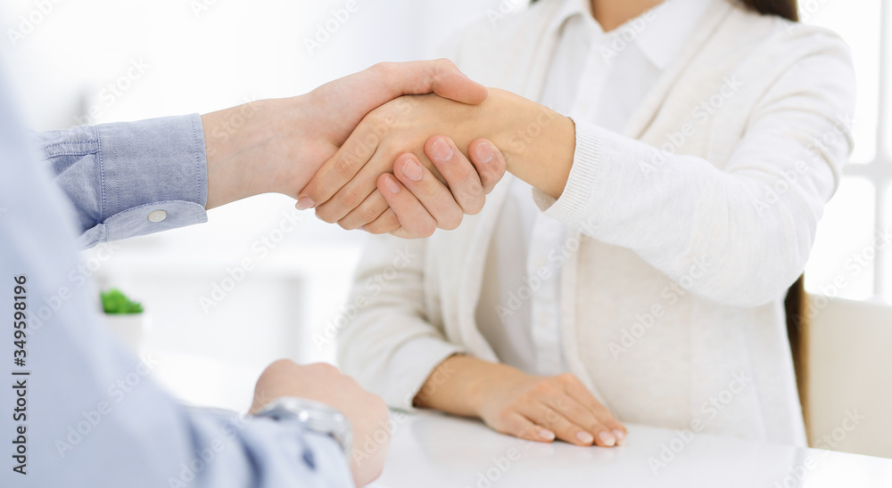 Casual dressed businessman and woman shaking hands after contract signing in white colored office. Handshake concept Casual dressed businessman and woman shaking hands after contract signing in white colored office. Handshake concept