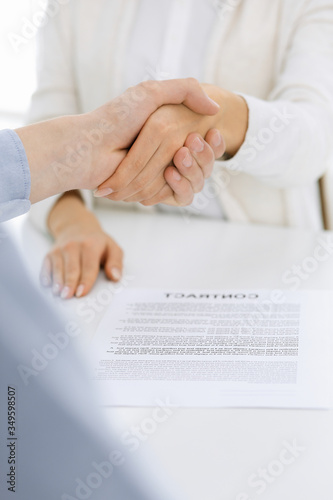 Casual dressed businessman and woman shaking hands after contract signing in white colored office. Handshake concept