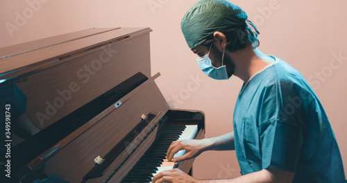 Medico o chirurgo in divisa suona il pianoforte per rilassarsi photo