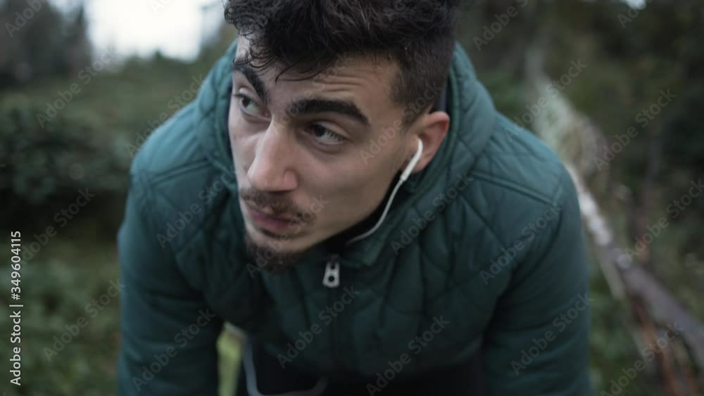 Young handsome man is running for exercise in an old pathway in woods. Man catch his breath and keeps going. Listening music while doing exercise.Slow motion,4k Young handsome man is running for exercise in an old pathway in woods. Man catch his breath and keeps going. Listening music while doing exercise.Slow motion,4k