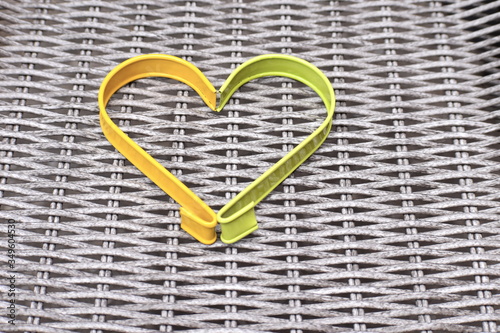 Yellow and green metal heart shaped frame against rustic background The most traditional shape is pointed at one end and indented at the opposite side looking like an inverted cone associate with love photo