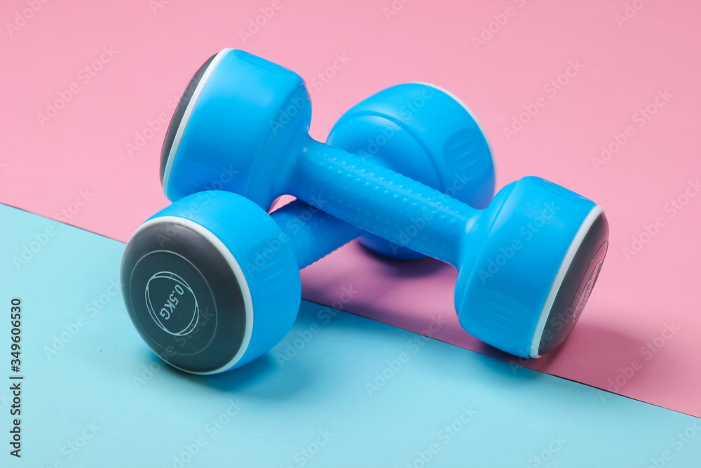 Plastic dumbbells on a blue pink pastel background. Plastic dumbbells on a blue pink pastel background.