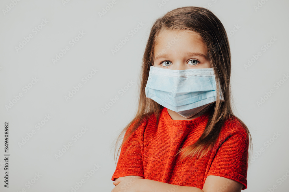 Little european girl wearing mask for protect pm2.5 and Covid-19. Sick child Little girls look at the camera posing in the studio in a red dress with a medical mask on her face. Copy space. Little european girl wearing mask for protect pm2.5 and Covid-19. Sick child Little girls look at the camera posing in the studio in a red dress with a medical mask on her face. Copy space.