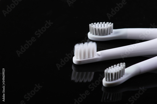 Three toothbrushes on a black reflective background