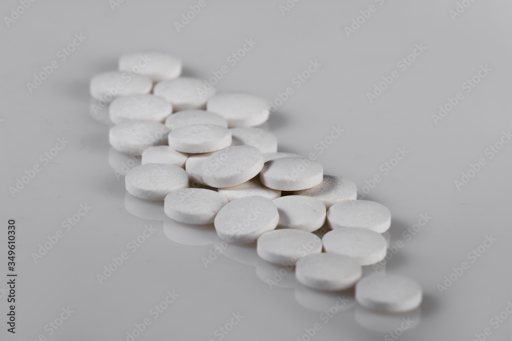 White pills on gray background close up White pills on gray background close up