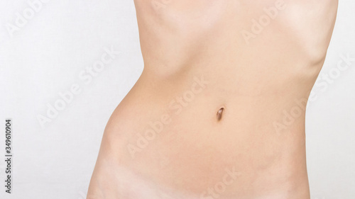 thin, slim belly of a young, beautiful girl isolated on gray, white background, there is an empty place