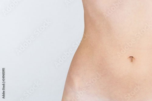 thin, slim belly of a young, beautiful girl isolated on gray, white background, there is an empty place
