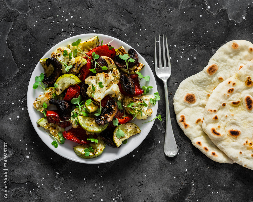 Vegetarian lunch - baked vegetables cauliflower, zucchini, mushrooms, peppers and tortillas on a dark background, top view Vegetarian lunch - baked vegetables cauliflower, zucchini, mushrooms, peppers and tortillas on a dark background, top view