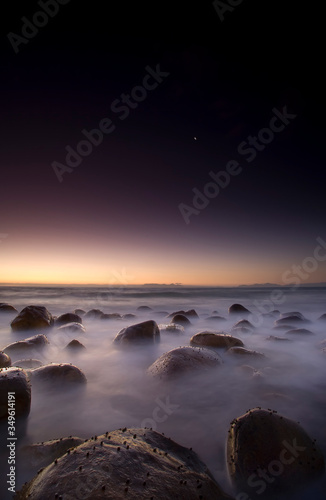 long exposure seascape with rocks and milky sea photo