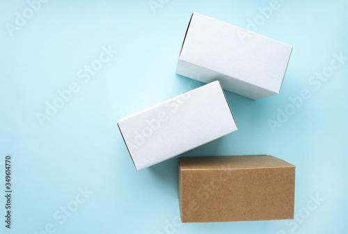 Three clean cardboard boxes are scattered on a blue background. Space for text. Selective focus.