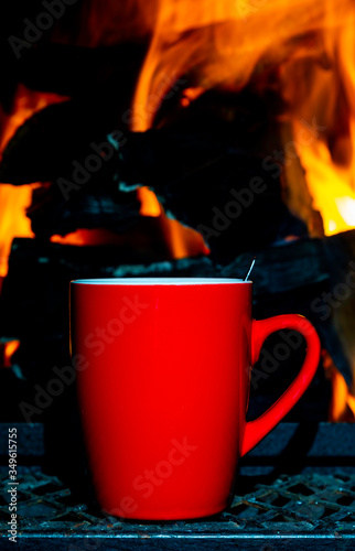 A Red coffee mug against a camp fire background.