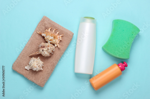 Bottle of shampoo with minerals, seashells, towel, sponge on blue background. Hair care. Top view. Flat lay