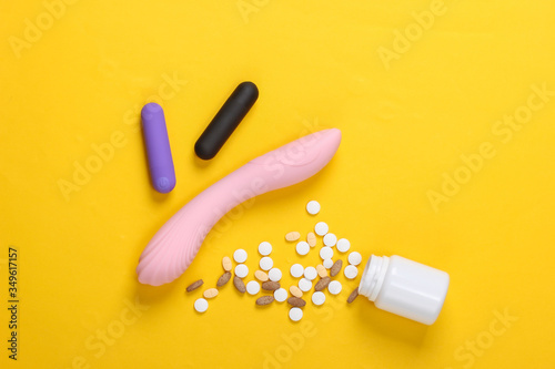 Sex toys and pills on yellow background. Sex stimulants.