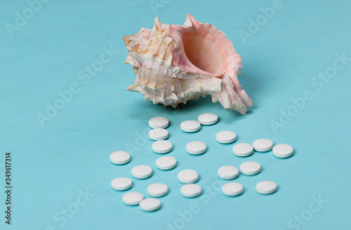 Mineral tablets (calcium) with seashells on a blue background