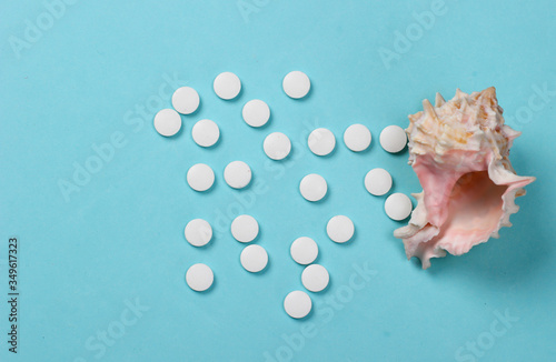 Mineral tablets (calcium) with seashells on a blue background