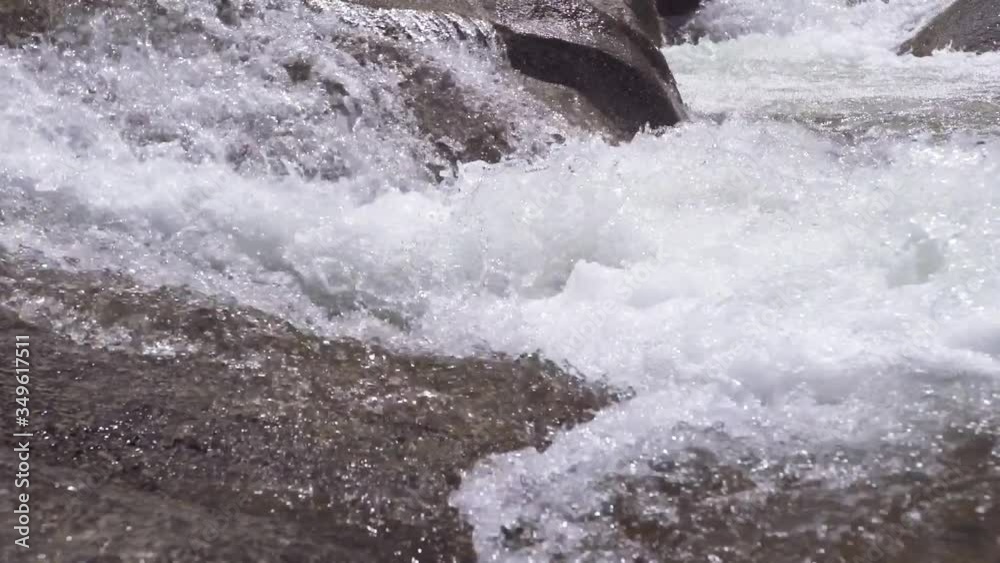 Extreme close up mountain stream flowing down across stones. cold brook with clear water flowing during summertime. Extreme close up mountain stream flowing down across stones. cold brook with clear water flowing during summertime.